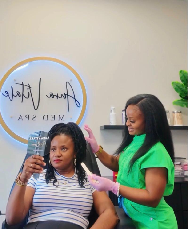 Aura Vitale provider in green scrubs consulting with a client holding a mirror